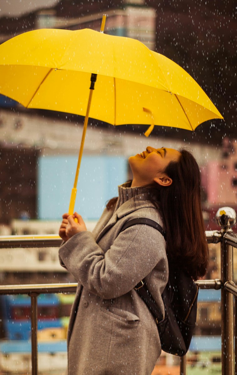 woman in gray jacket holding yellow umbrella